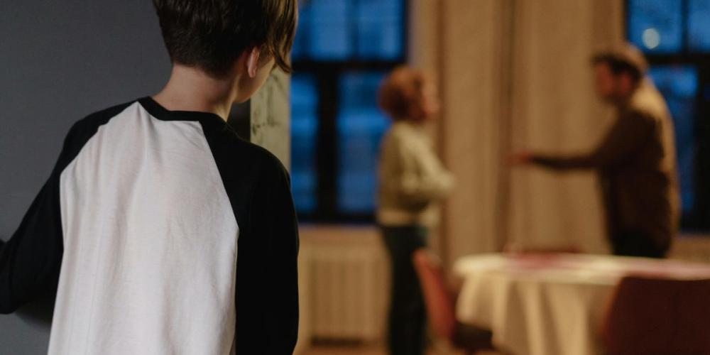Kind kijkt om de hoek naar ruziënde ouders