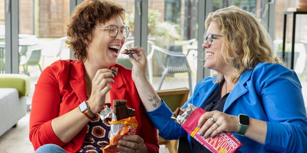 Dame stopt chocolade in de mond bij vrolijke vriendin