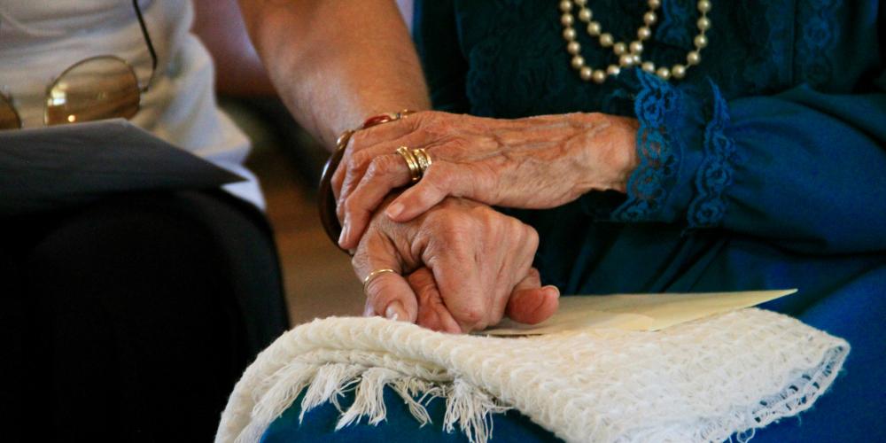 oudere dame en jongere damen houden elkaars hand vast