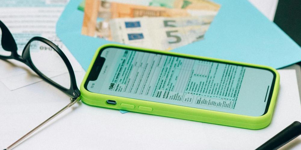 bril, geld, vergrootglas en rekenblad op gsm