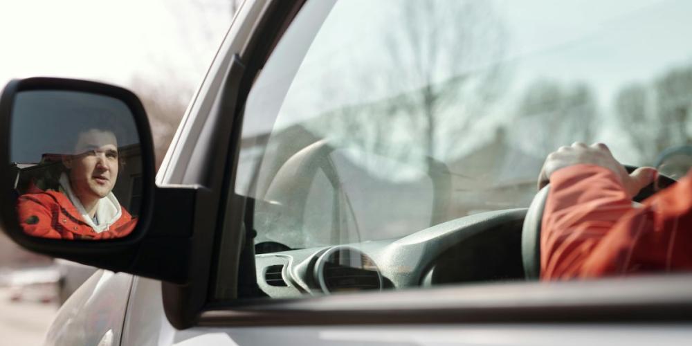Autobestuurder gezien via buitenspiegel