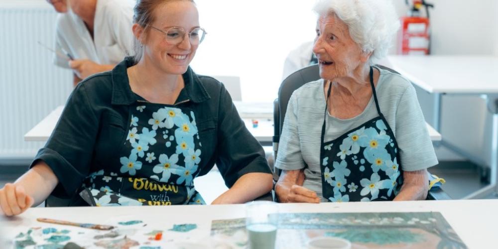 deelneemster Herschilderingen naast begeleidster reageert verwonderd en uitgelaten