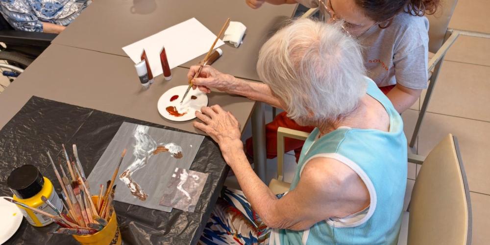 dame schildert naarstig met begeleidster