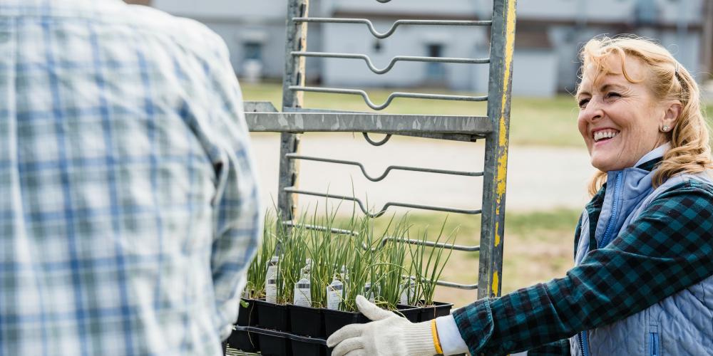tuinierende dame die plantjeskar duwt buit glimlacht blij 