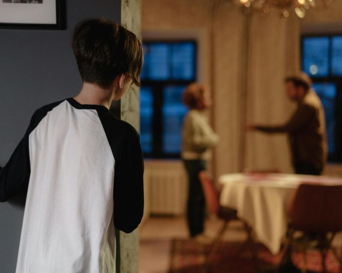 Kind kijkt om de hoek naar ruziënde ouders