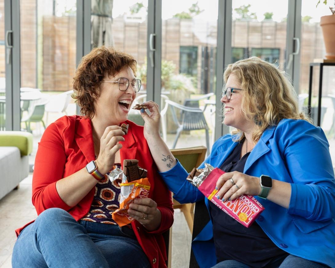 Dame stopt chocolade in de mond bij vrolijke vriendin