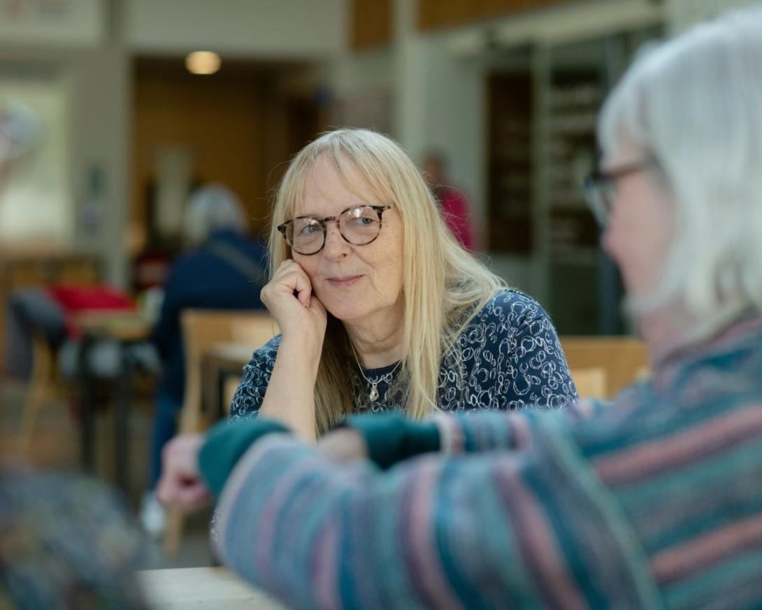 dame in leefruimte kijkt liefdevol naar oudere naaste