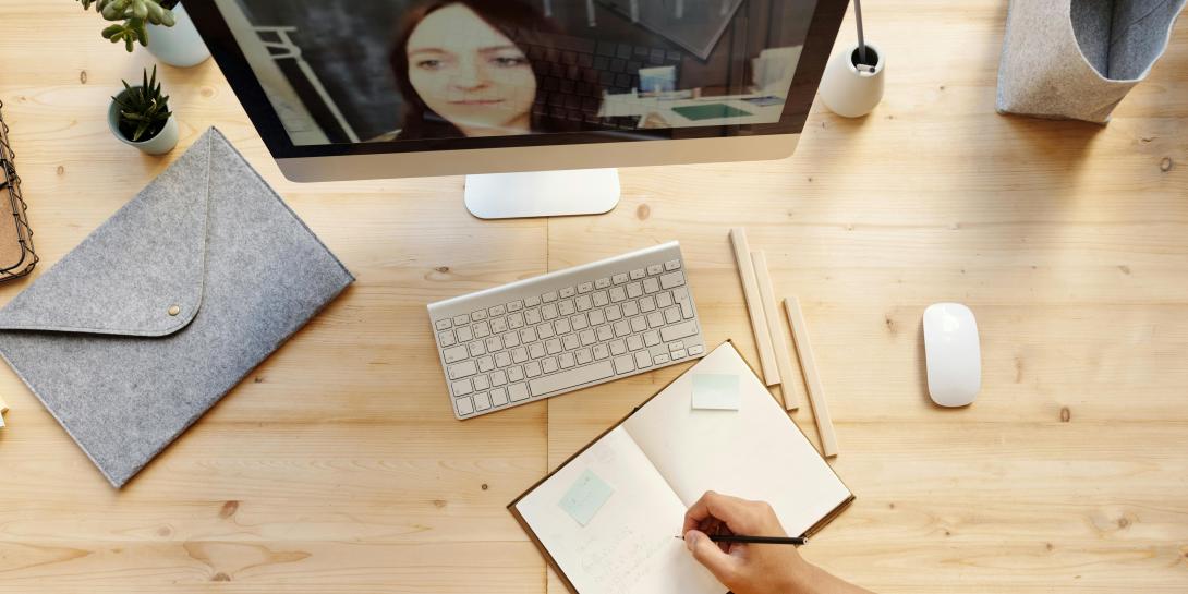 iemand maakt notities aan bureau bij online les