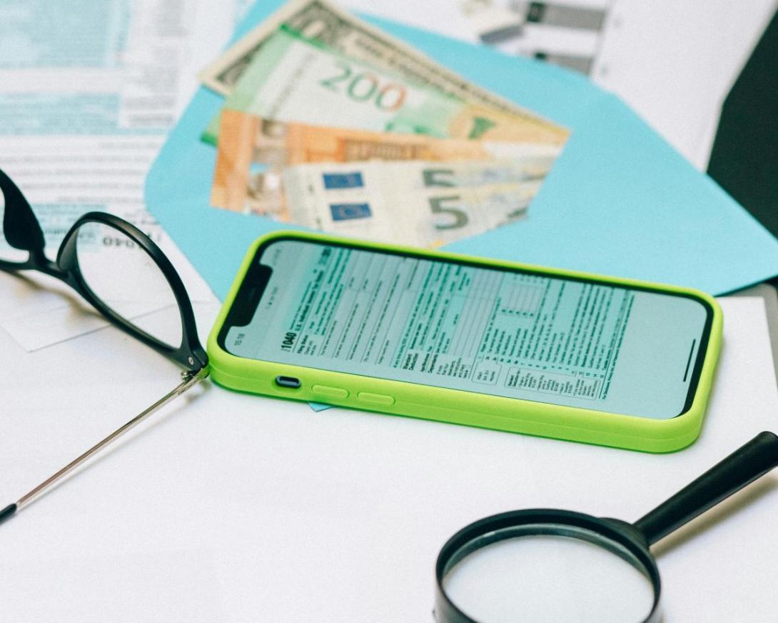 bril, geld, vergrootglas en rekenblad op gsm