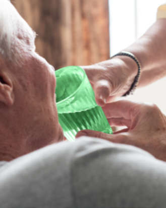Oudere man wordt geholpen met water drinken uit een gekleurd glas