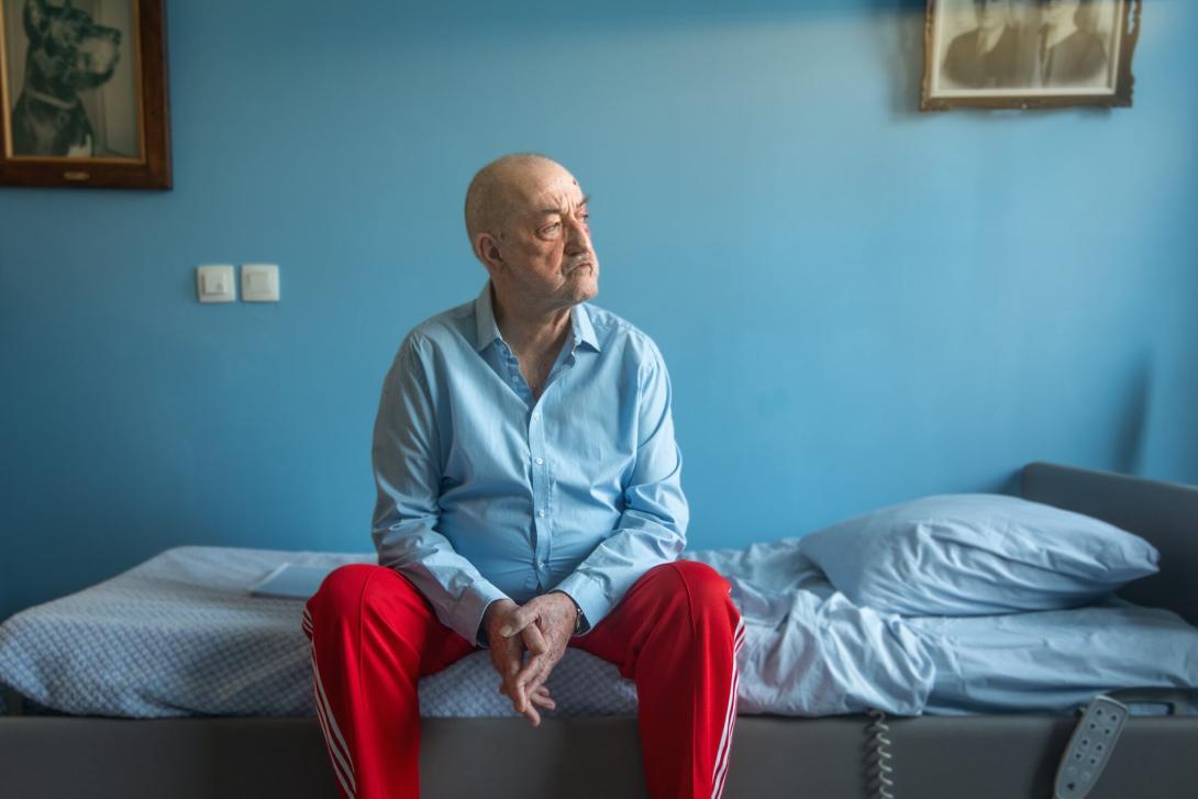 Personage Horst zit op bed starend door raam 