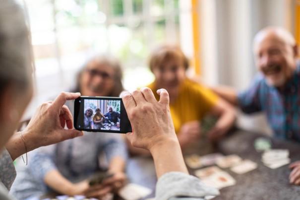 iemand neemt een gsm-foto van drie vriendelijke oudere mensen