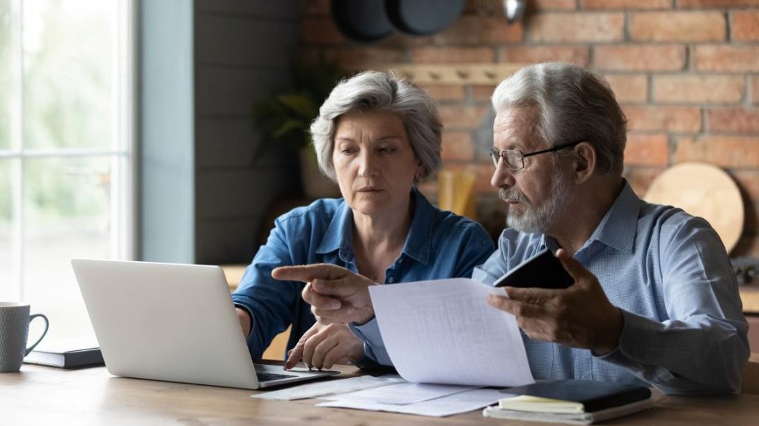 Man en vrouw overleggen met papieren en laptop