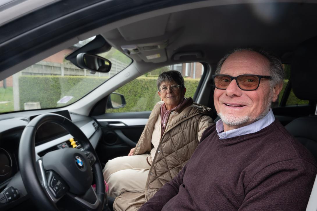 bestuurder en passagier kijken glimlachend door autoraam 