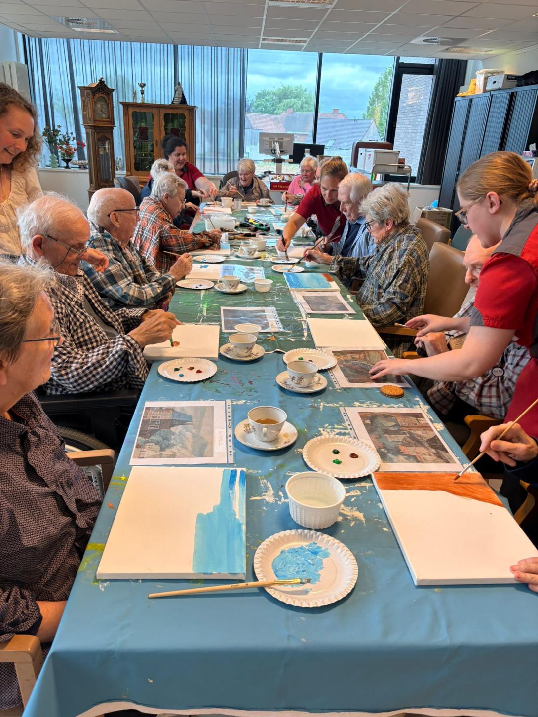 grote groep oudere mensen aan lang tafel om te schilderen