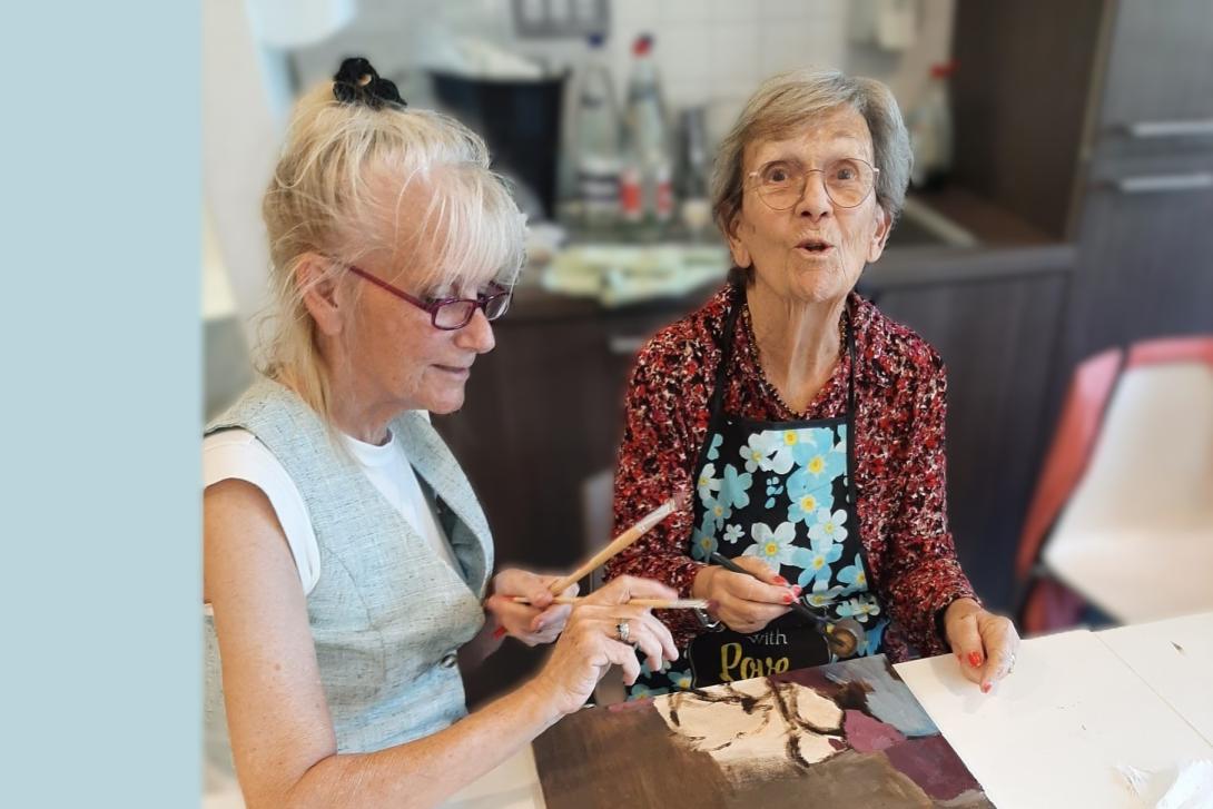 Schilderende oudere dame kijkt enthousiast in de lens