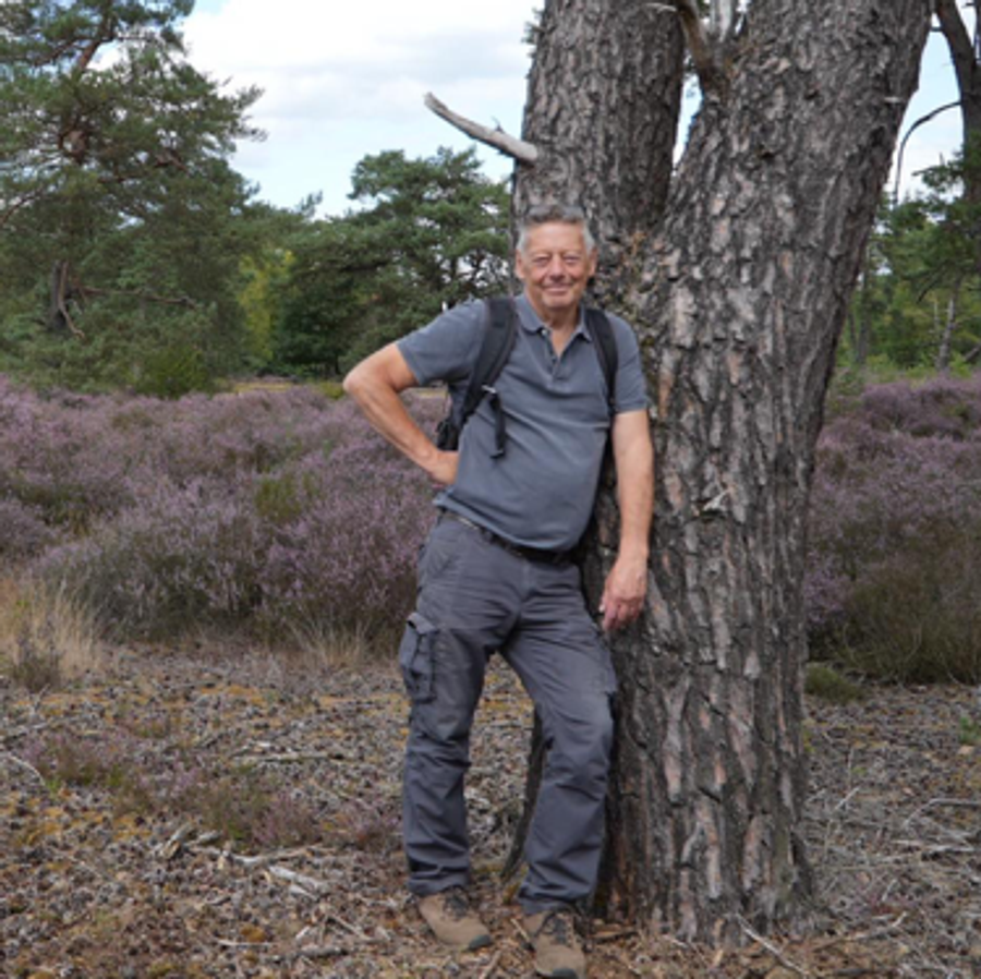Portret van Leo Maes, leunend tegen een boom in de natuur
